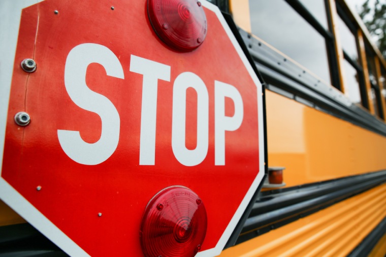 Stop sign on the side of a yellow school bus