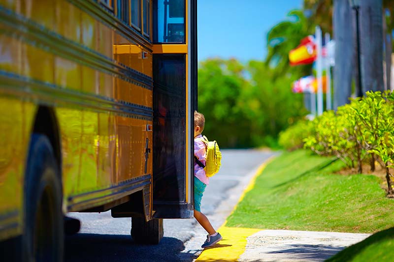Kid walking into a 14 passenger school bus